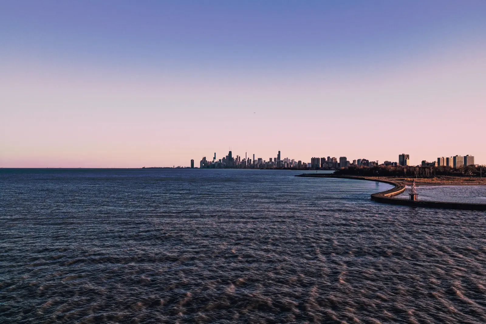 The Chicago skyline seen small across Lake Michigan at blue hour.