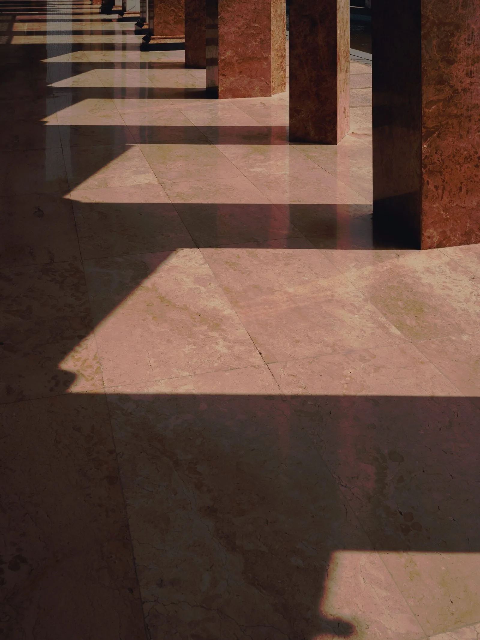 Columns casting shadows across a marble floor.