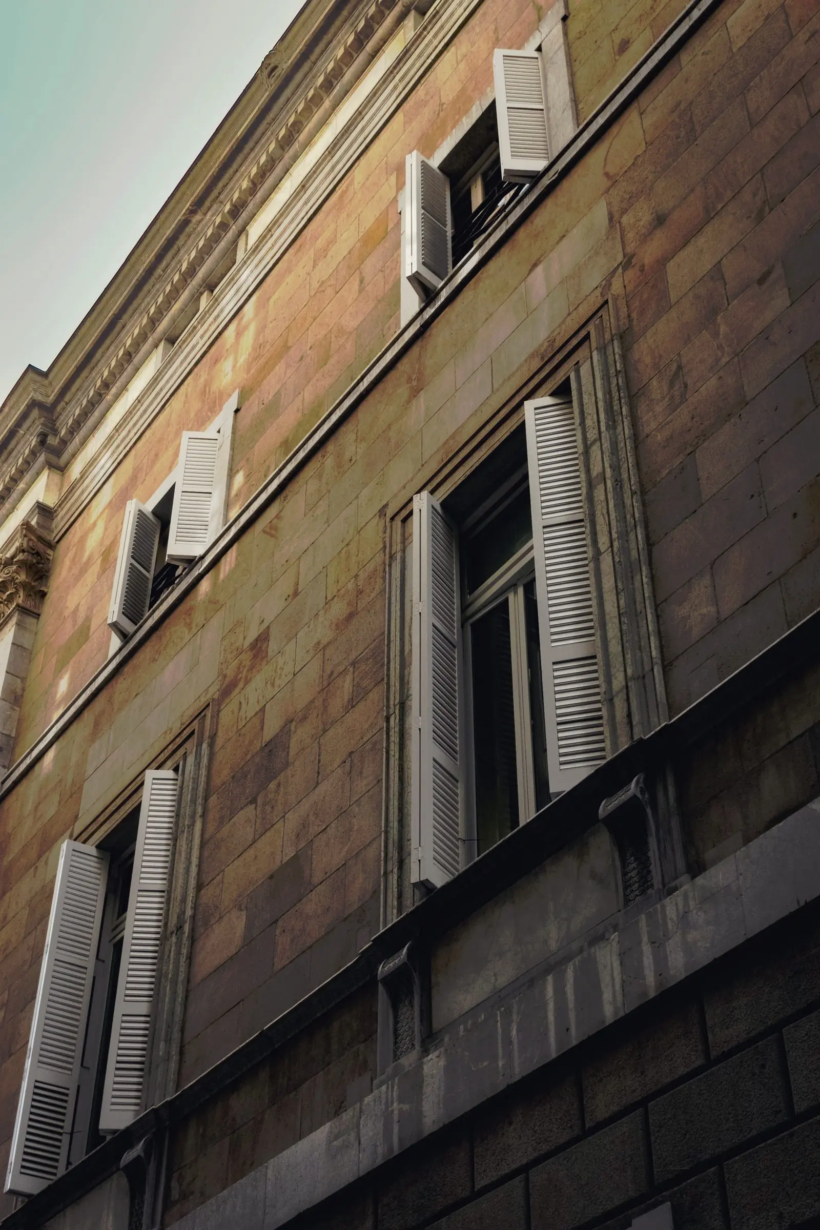 A stone facade with open shutters.